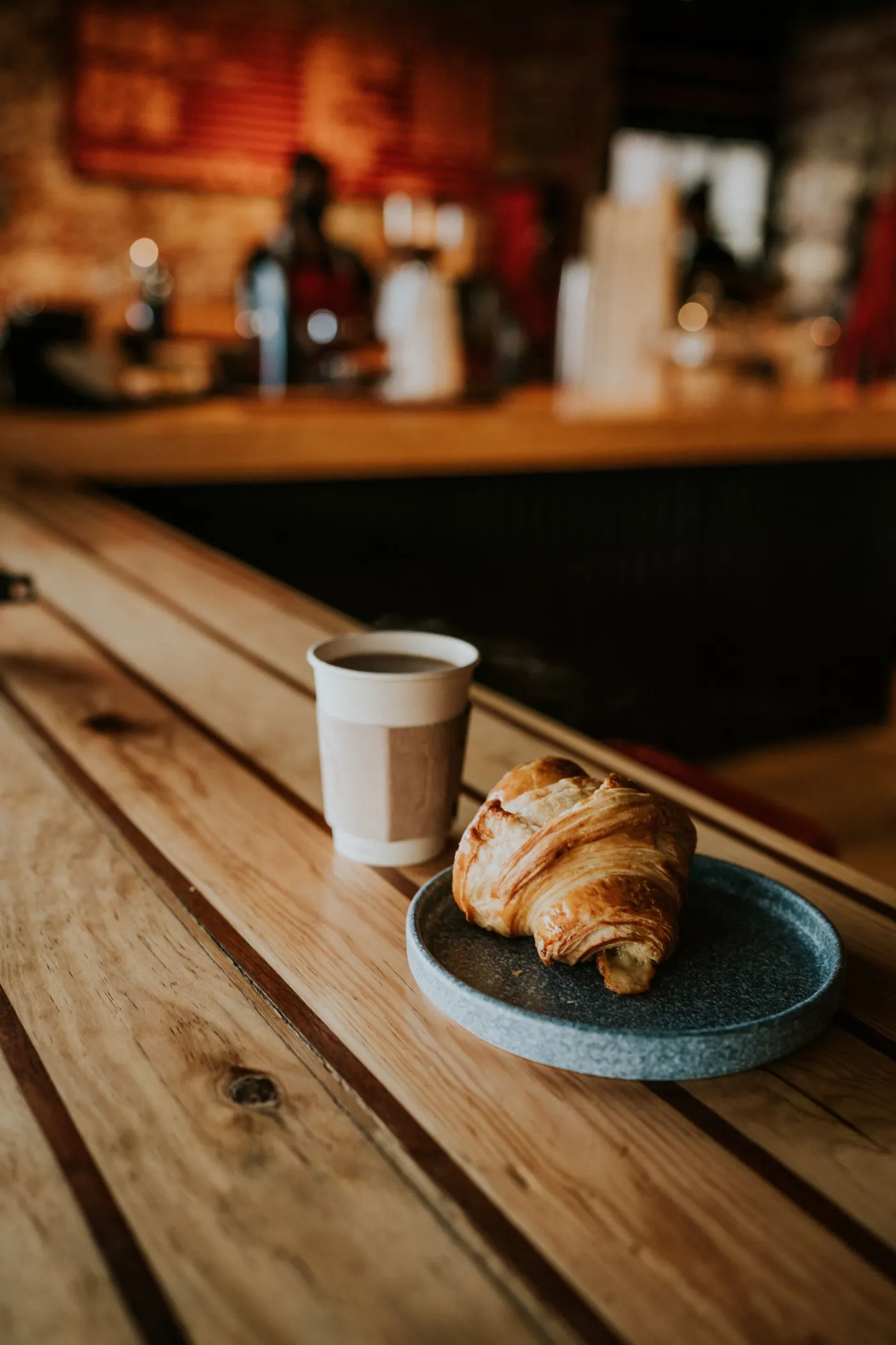 Frischer Kaffee und Croissant auf der Holztheke am Morgen